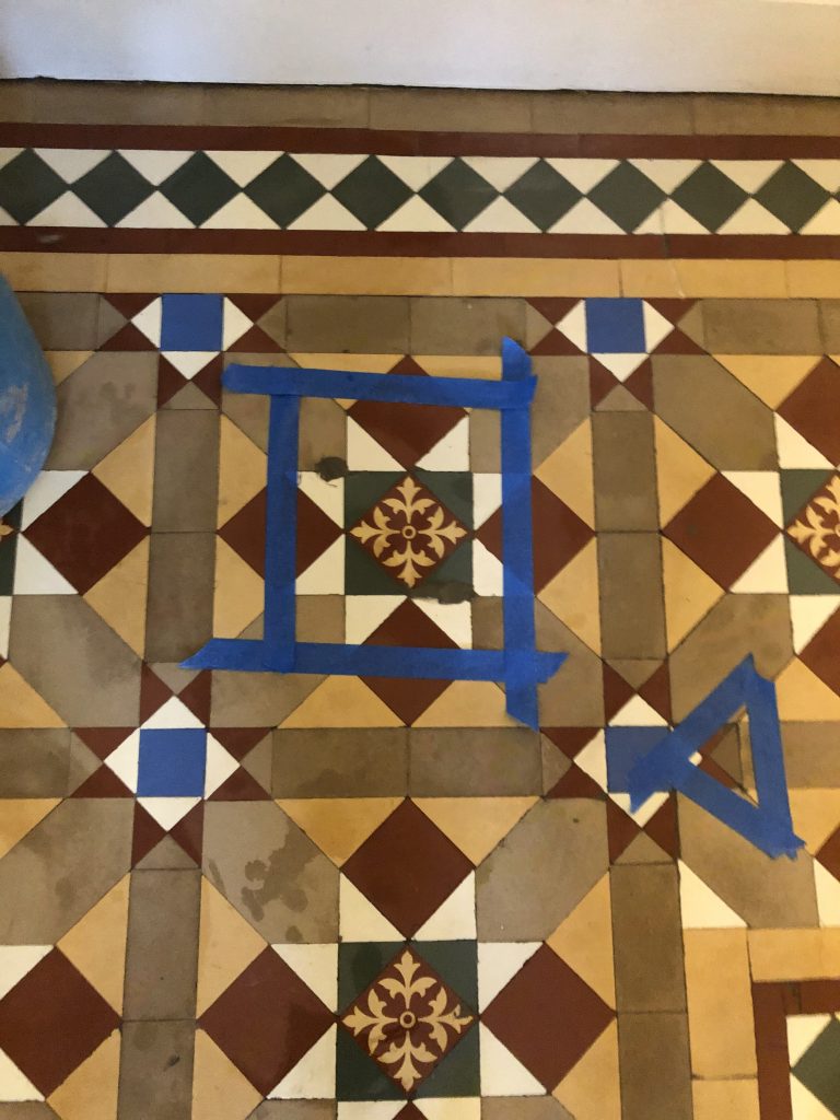 repairs to tiles in Victorian hallway that have been marked with blue tape