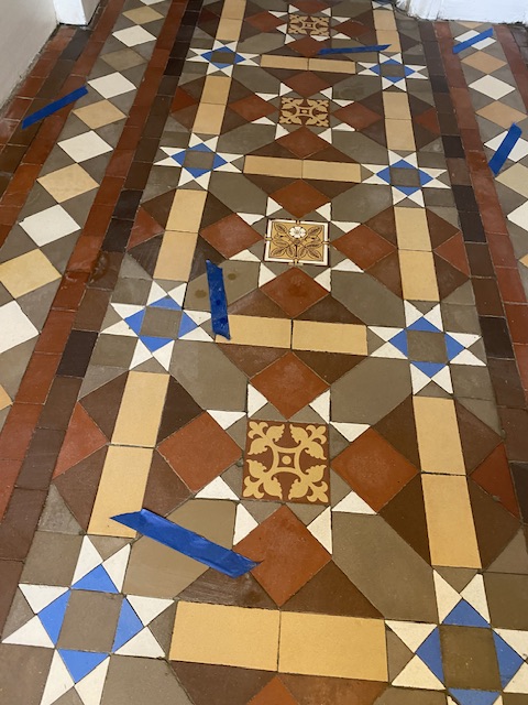 Victorian hallway tiles that have been relaid and marked clearly with blue tape
