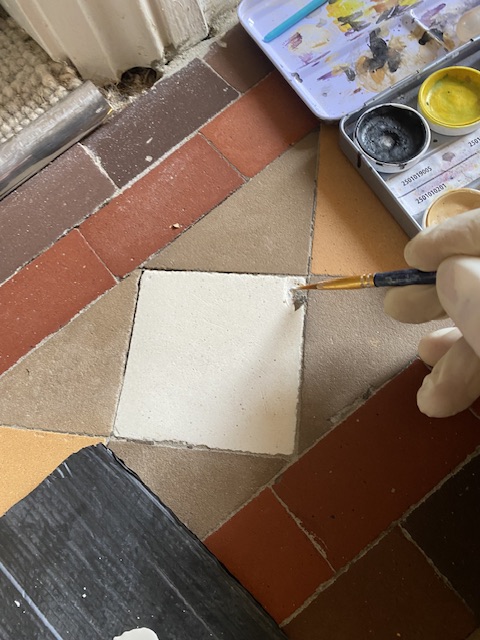 touching up a chip in an original Victorian hallway tile . ( Before)