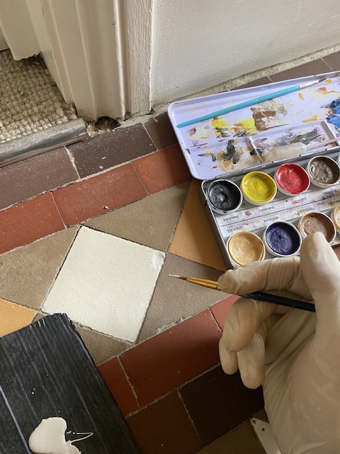 touching up a chip in an original Victorian hallway tile . ( After)