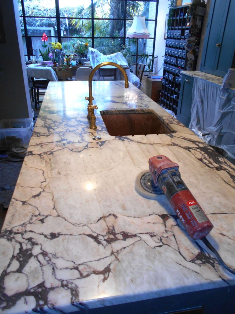 Deeply veined marble island worktop being sealed and buffed