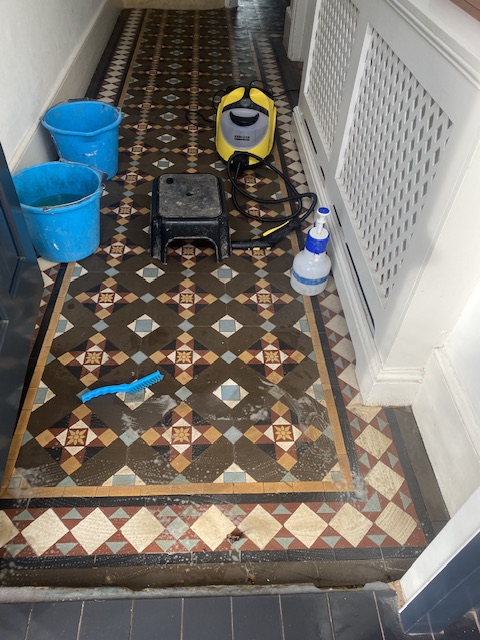 Victorian geometric hallway tiles being cleaned and very dirty 