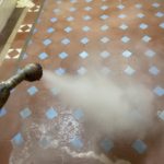 Victorian tiles in hallway being steam cleaned. You can see a fairly powerfull jet of steam to blast out old oil and wax from inside the tiles