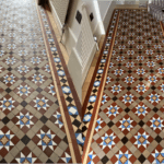 geometric hallway deep cleaned and sealed. An attractive tiled hallway with brown , red, blue , white and yellow tiles in a star like geometric pattern. These tiles were restored and color enhanced with a special enhancer to really bring out the color