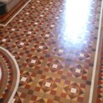 attractive shiny Victorian geometric tiles in a hallway. Tiles are yellow, coffee, red, black and white. They where deep cleaned and waxed .