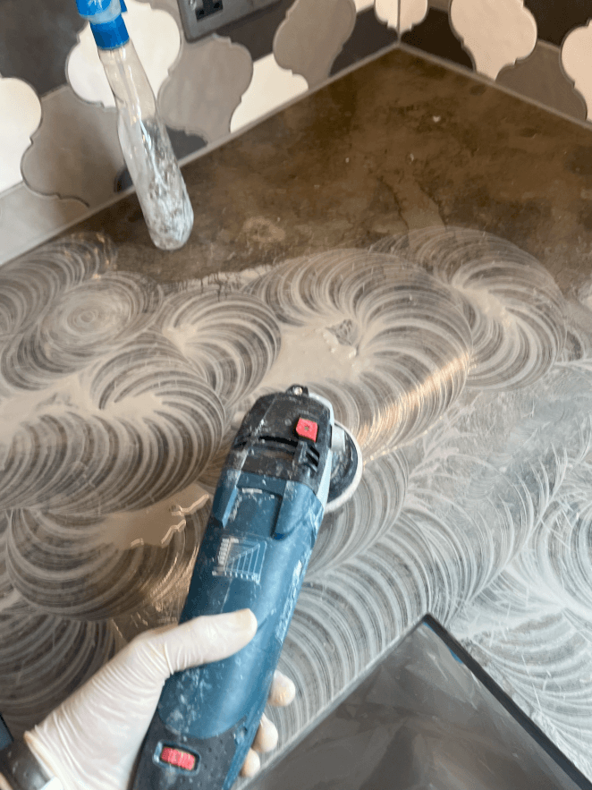 Dark marble kitchen worktop refurb job, using hand help polisher to hone surface with diamond pads. Early stage of stone polishing process